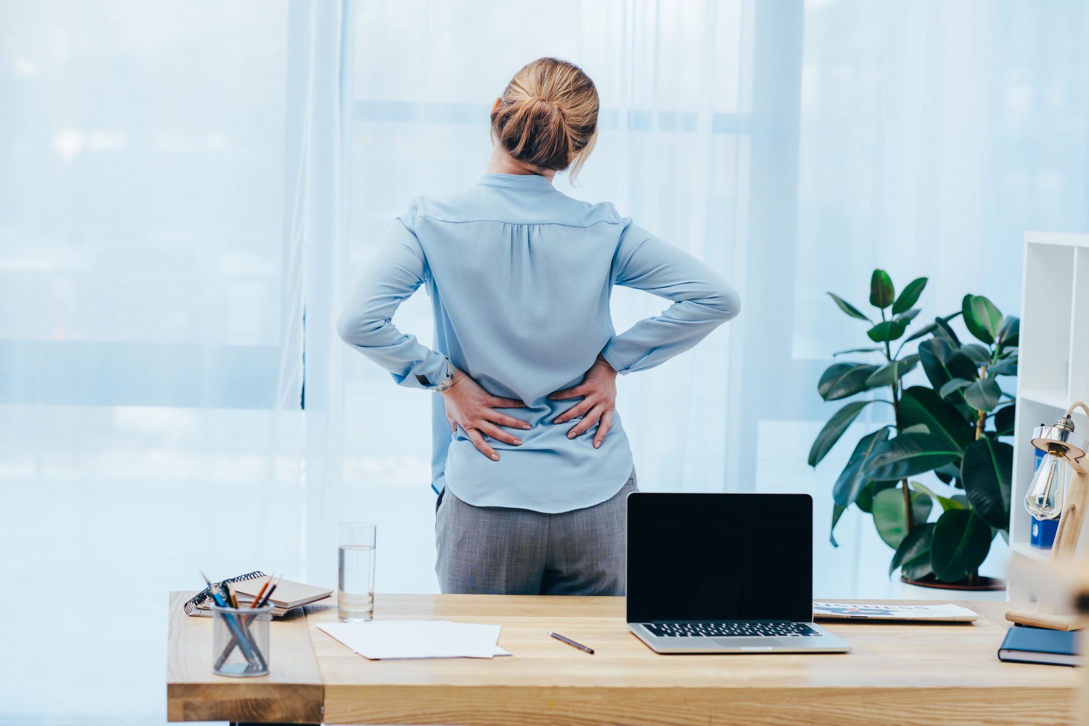 rear view of businesswoman with backplain in office Pain Management in Albuquerque